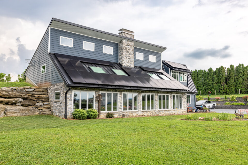 Ground level shot of a large south facing house with solar panels on the roof and a large sunroom for passive solar heating in Lancaster, PA